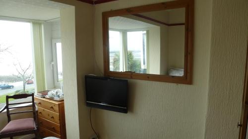 a television on a wall with a mirror at Whitehall Guest House in Colwyn Bay