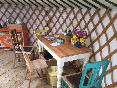 a wooden table in a yurt with chairs and flowers at The Yurt in Isle of Gigha