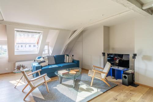 un salon avec un canapé bleu et des chaises dans l'établissement STRAS'LOFT - Hypercentre - Haut de Gamme - Cathédrale - Confort - Calme, à Strasbourg