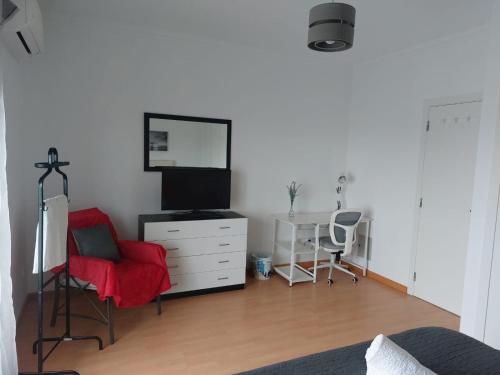 a bedroom with a dresser with a television and a chair at Vivenda Cordeiro in Bárrio
