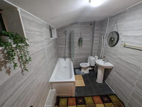 Un baño con bañera, inodoro y lavabo. en London E2 Rooms, en Londres