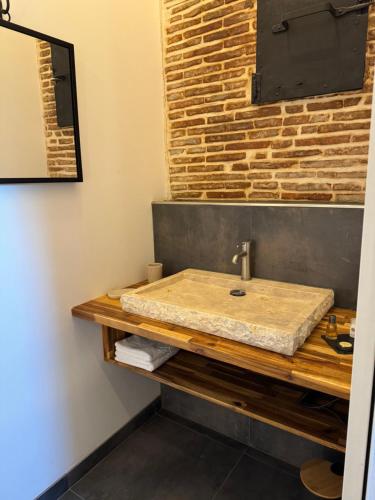 a bathroom with a sink and a brick wall at Domaine Le Petit Moulin in Lachy