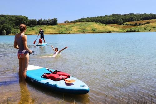 a woman standing next to a paddle board on a lake at Domaine La Barbe ! in Lalanne-Arqué