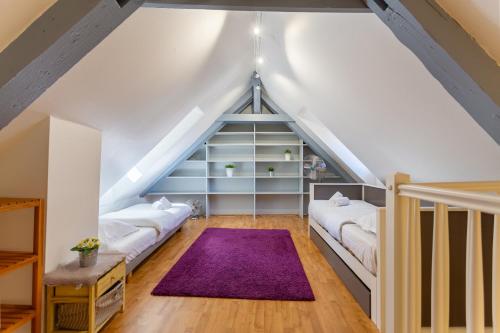 - une chambre mansardée avec 2 lits et un tapis violet dans l'établissement Evasion Cathédrale, à Strasbourg
