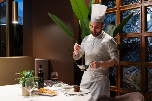 a man in a chefs hat is preparing food at Hotel Minerva in Arezzo