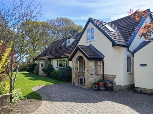 a white house with a gambrel roof and a driveway at The Herons in Goldsborough