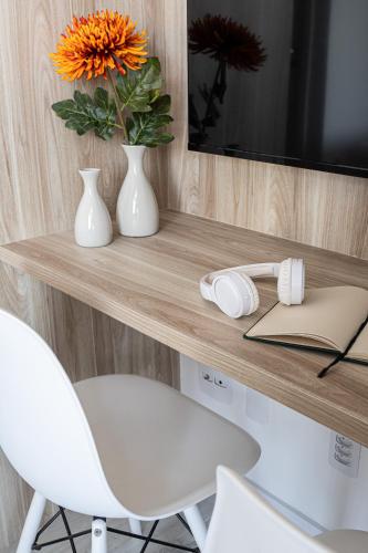 a desk with a white chair and a vase with a flower at Hub Boa Vista by Viva - Prédio novo próximo ao Autódromo de Interlagos com lavanderia e academia in Sao Paulo