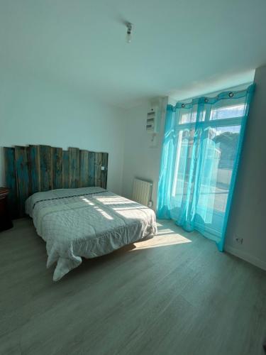 une chambre avec un lit et une grande fenêtre dans l'établissement Maison de Famille La Bernerie, à La Bernerie-en-Retz