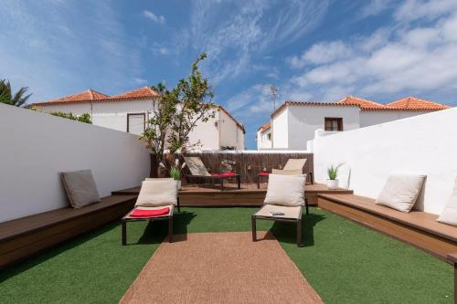 a patio with two chairs and green grass at Villa Tricia 6 Bedroom Las Americas in Playa de las Americas