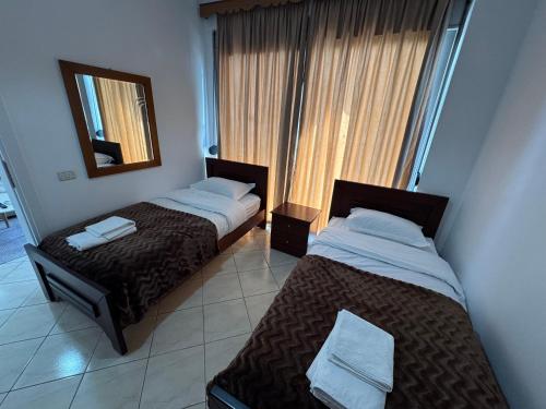 two beds in a room with a mirror and a window at Comfort Apartments Promenade in Sarandë