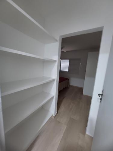 a closet with white shelves in a room at Apartamento Família Termas in Gravatal