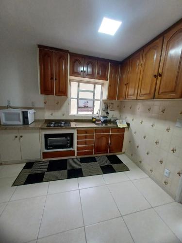 a kitchen with wooden cabinets and a stove top oven at Apartamento Família Termas in Gravatal