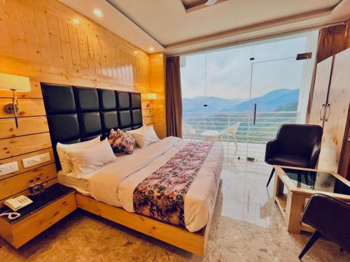 a bedroom with a large bed and a large window at The Classic Hill View Hotel, Near JW Marriott Mussoorie in Mussoorie