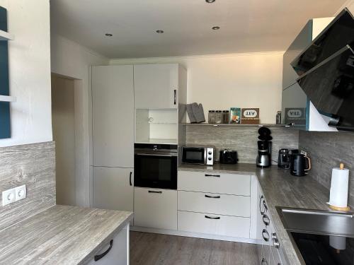 a kitchen with white cabinets and a stove top oven at Ferienhaus Morgenstern in Wilhelmshaven