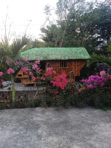 a small house with a green roof and flowers at Silong Bitaoy Beach Resort in Santa Cruz