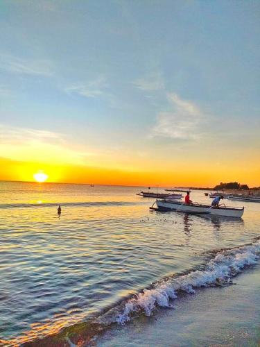 two boats on the water at the beach at sunset at Silong Bitaoy Beach Resort in Santa Cruz