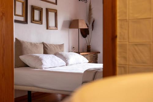 a bedroom with a bed with white sheets and pillows at Casal da Serrana in Óbidos