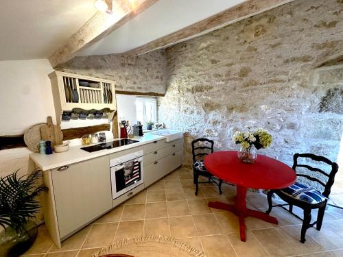 - une cuisine avec une table rouge dans une pièce dans l'établissement L'Herbe Pot, à Salles