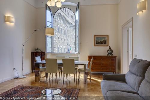 a living room with a table and chairs and a window at Le Farine della Signoria Apartments by Mamo Florence in Florence