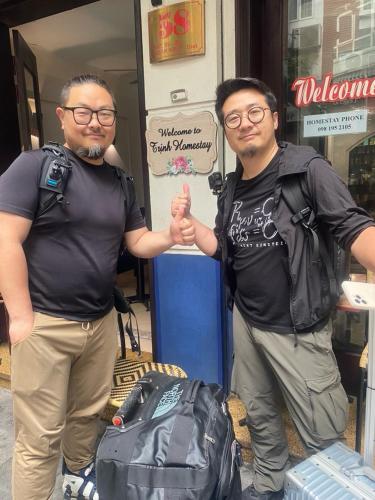 two men are holding hands while standing next to a bag at Trinh Homestay in Hanoi