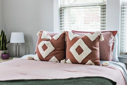 a bed with pink and white pillows on it at Elmwood Park Retreat Renovated 3 Bed 2 Bath DT in Columbia