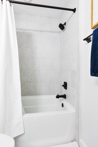 a white bath tub in a bathroom with a blue towel at Elmwood Park Retreat Renovated 3 Bed 2 Bath DT in Columbia