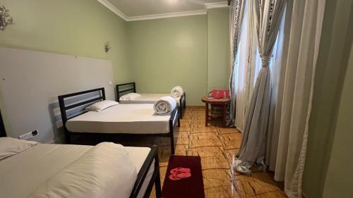 a room with two beds and a table and a window at Lush Garden Hostel in Arusha