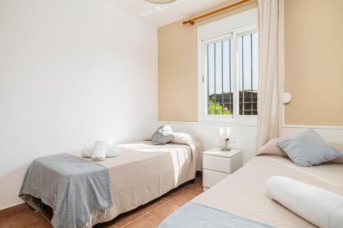 ein Schlafzimmer mit zwei Betten und einem Fenster in der Unterkunft Jardín del Golf apartamento con jardín privado in Chiclana de la Frontera