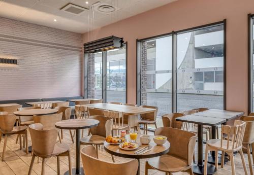 a restaurant with tables and chairs and windows at B&B HOTEL Bordeaux Bassins à flot in Bordeaux