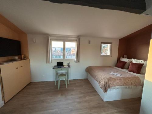 une chambre avec un lit et une table et deux fenêtres dans l'établissement L'Origan, Studio sous les toits, à Draguignan
