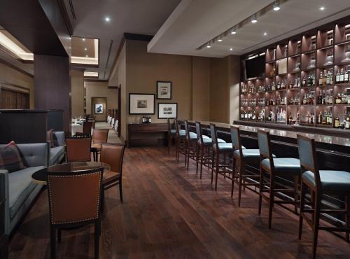 a bar in a restaurant with chairs and a counter at Omni Louisville Hotel in Louisville