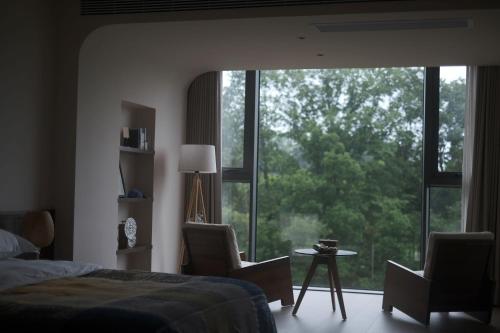 1 dormitorio con 1 cama, 2 sillas y una ventana grande en 张家界大峡谷迴音森林乡村民宿, en Cili