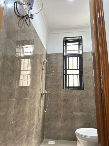 a bathroom with a shower with a toilet and a window at Zaya Residency in Kampala