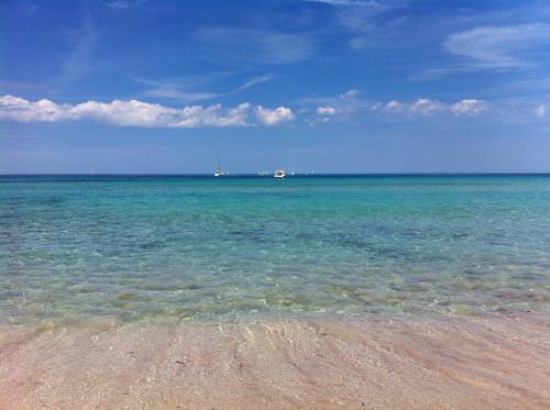 a beach with the ocean and a boat in the distance at Case Vacanze Terra Sinus in Terrasini