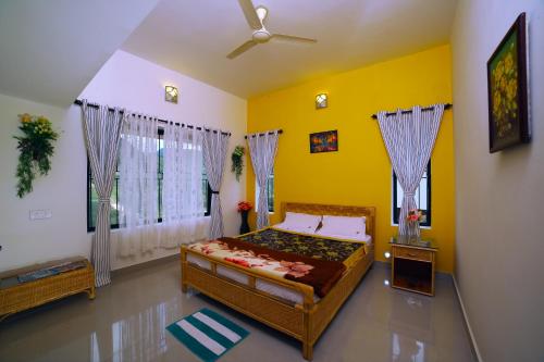 a bedroom with a bed and a yellow wall at Vrindhavan Mist City Resorts in Kanthalloor
