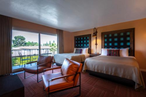 a hotel room with two beds and a balcony at Hotel Pepper Tree Boutique Kitchen Studios - Anaheim in Anaheim