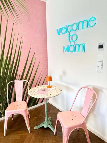 two pink chairs and a table and a table and chairs at Miami Vice Appartement mit Balkon & Flussblick-Das Alpenzeit im Zentrum mit Parkplatz in Bad Aussee