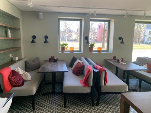 a waiting room with couches and tables and windows at Victoria hotell & apartments Fredrikstad in Fredrikstad