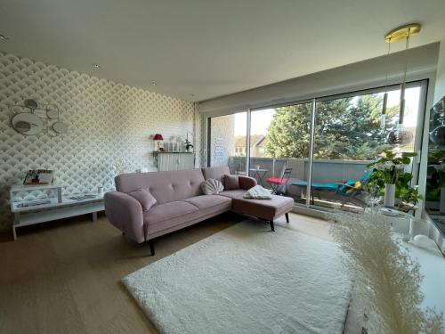 - un salon avec un canapé rose et une grande fenêtre dans l'établissement Appartement le Banville - lumineux proche hopital, à Moulins