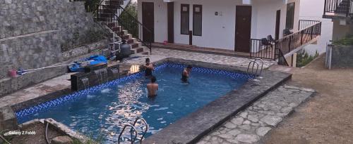 een groep mensen in een zwembad bij Vatika Resorts Cottages in Shogi