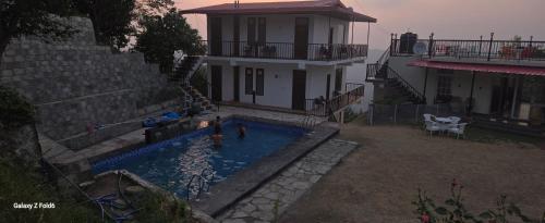 een huis met een zwembad voor een huis bij Vatika Resorts Cottages in Shogi