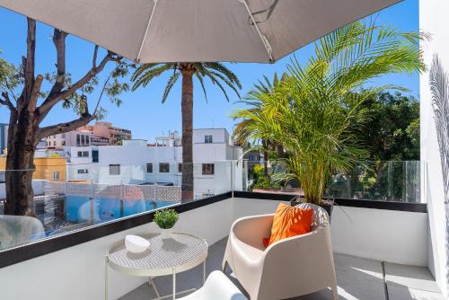 a balcony with a table and chairs and an umbrella at Las Dunas de Santa Catalina Boutique House in Las Palmas de Gran Canaria