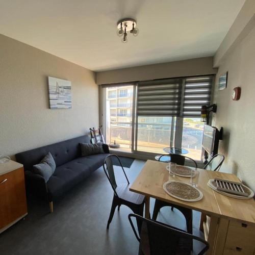 un salon avec un canapé bleu et une table dans l'établissement L'arbre du voyageur, à Les Sables-dʼOlonne