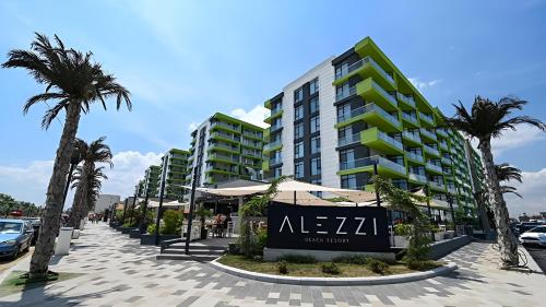 a building on a street with palm trees and a sign at Alezi Apartamente in Mamaia Sat/Năvodari