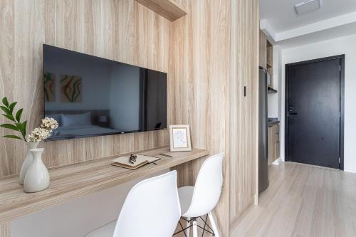 a living room with a tv and two white chairs at Hub Boa Vista by Viva - Prédio novo próximo ao Autódromo de Interlagos com lavanderia e academia in Sao Paulo
