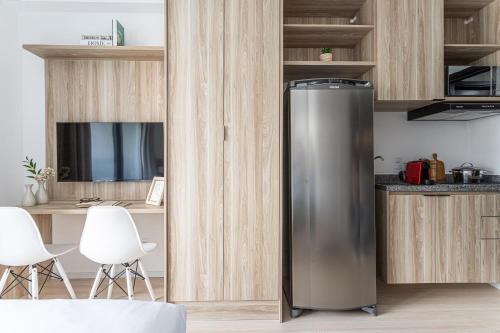 a stainless steel refrigerator in a kitchen with wooden cabinets at Hub Boa Vista by Viva - Prédio novo próximo ao Autódromo de Interlagos com lavanderia e academia in Sao Paulo