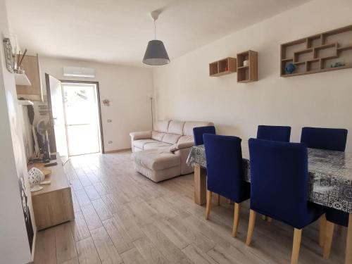 a living room with a table and blue chairs at Villa Denise in Pulsano