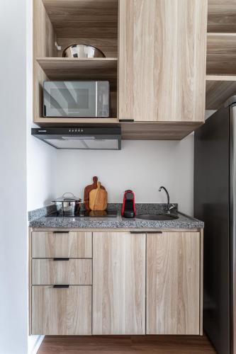 a kitchen with wooden cabinets and a microwave at Hub Boa Vista by Viva - Prédio novo próximo ao Autódromo de Interlagos com lavanderia e academia in Sao Paulo