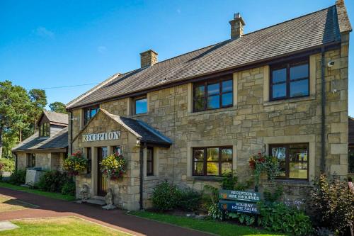 un antiguo edificio de piedra con un letrero en la parte delantera en Percy Wood Country Park, en Swarland