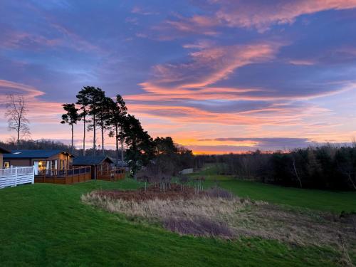 una casa en un campo con una puesta de sol en el fondo en Percy Wood Country Park, en Swarland